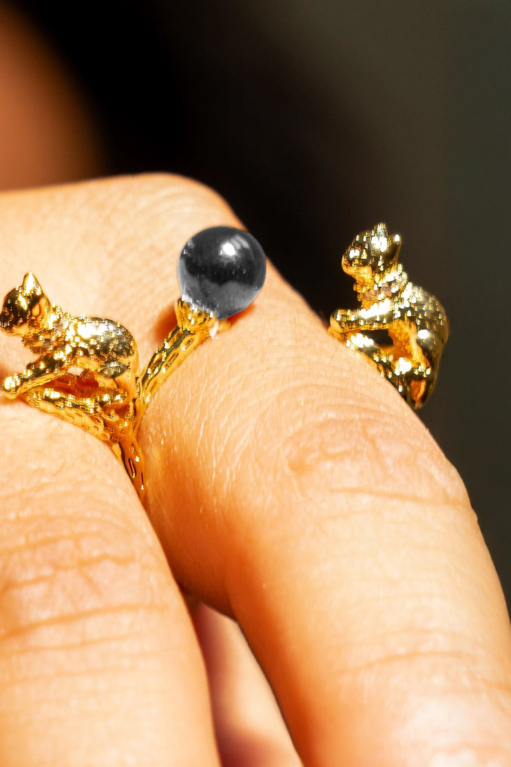 Anillo Cat's Cradle chapado en oro con hematita azul en mano