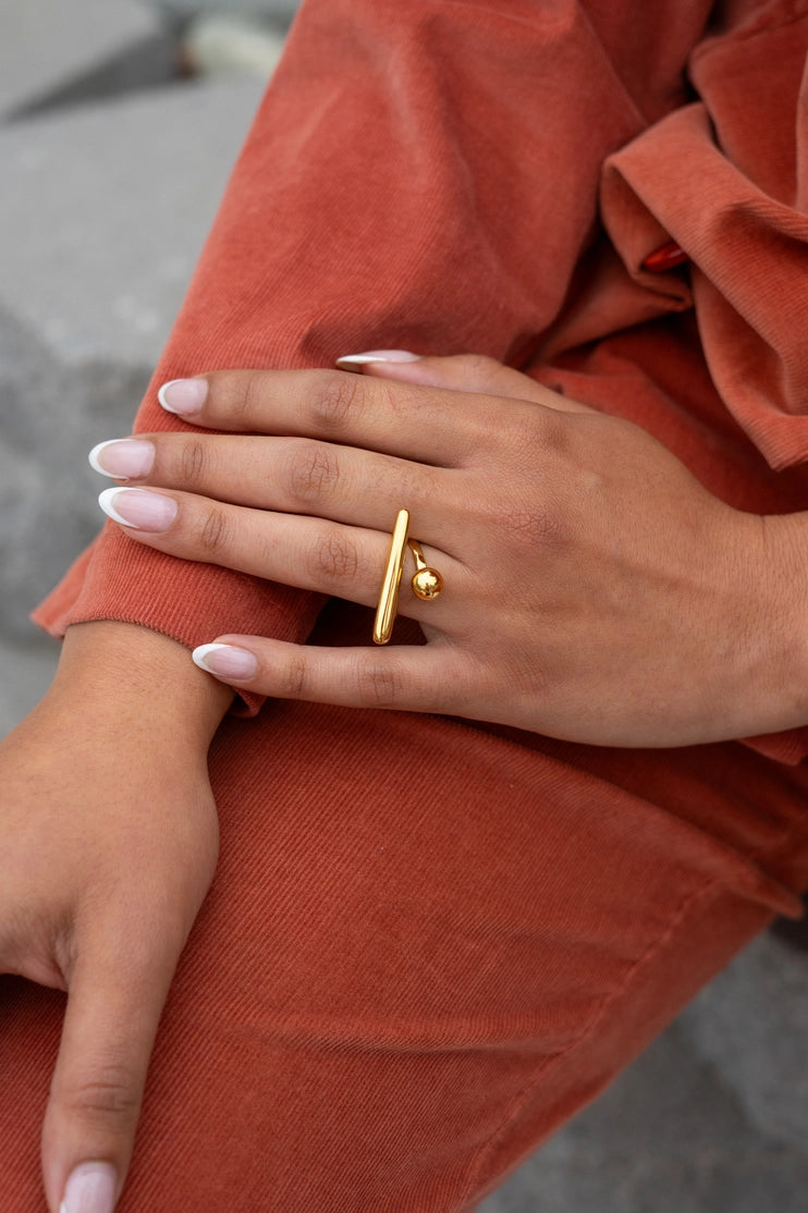 Anillo de equilibrio dorado estilo lifestyle con outfit terracota