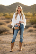 Modelo luciendo la bolsa transparente horizontal con flecos café y escena del desierto pintada a mano